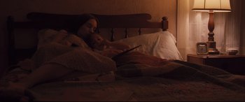 Movie still from “Ain't Them Bodies Saints” (2013), directed by David Lowery – A woman and a child in bed with a tablet; Medium shot, High angle