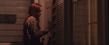 Movie still from “Ain't Them Bodies Saints” (2013), directed by David Lowery – A woman standing in front of an open door; Medium shot, Over the shoulder angle