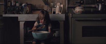 Movie still from “Ain't Them Bodies Saints” (2013), directed by David Lowery – A little girl sitting on the floor with a bowl of food; Medium shot, High angle
