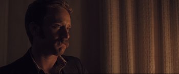 Movie still from “Ain't Them Bodies Saints” (2013), directed by David Lowery – A person wearing a suit and tie; Close Up shot, Over the shoulder angle