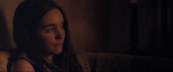 Movie still from “Ain't Them Bodies Saints” (2013), directed by David Lowery – A woman sitting on a couch in a dark room; Close Up shot, Over the shoulder angle