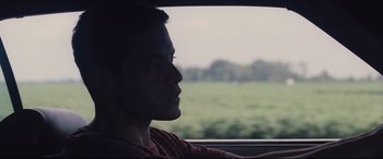 Movie still from “Ain't Them Bodies Saints” (2013), directed by David Lowery – A man sitting in a car looking out the window; Close Up shot, Over the shoulder angle