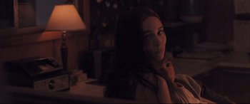 Movie still from “Ain't Them Bodies Saints” (2013), directed by David Lowery – A woman sitting on a couch in a dark room; Close Up shot, Over the shoulder angle