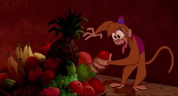 Movie still from “Aladdin” (1992), directed by John Musker – A cartoon of a monkey holding a piece of fruit; Medium shot, Over the shoulder angle