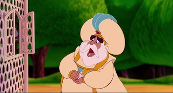 Movie still from “Aladdin” (1992), directed by John Musker – A cartoon of a man with a white beard and a blue hat; Medium shot, Over the shoulder angle