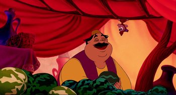 Movie still from “Aladdin” (1992), directed by John Musker – A man with a beard and a mustache is smiling; Medium shot, High angle