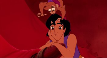 Movie still from “Aladdin” (1992), directed by John Musker – A man and a monkey are sitting next to each other on a bed; Medium shot, Overhead angle