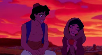 Movie still from “Aladdin” (1992), directed by John Musker – A man and a woman are sitting next to each other in front of a sunset; Wide shot, Overhead angle