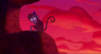 Movie still from “Aladdin” (1992), directed by John Musker – A monkey sitting on top of a rock; Medium shot, Low angle