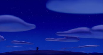 Movie still from “Aladdin” (1992), directed by John Musker – A person standing on top of a hill under a blue night sky; Extreme Wide shot, Low angle