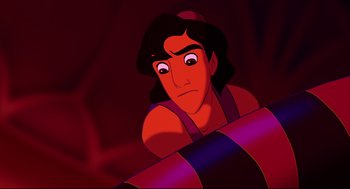 Movie still from “Aladdin” (1992), directed by John Musker – A man with long black hair and a red shirt; Close Up shot, High angle