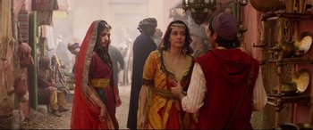 Movie still from “Aladdin” (2019), directed by Guy Ritchie – A group of people standing next to each other on a street; Medium shot, Over the shoulder angle