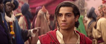 Movie still from “Aladdin” (2019), directed by Guy Ritchie – A man in a red shirt is looking at the camera; Close Up shot, Over the shoulder angle