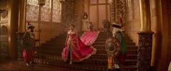 Movie still from “Aladdin” (2019), directed by Guy Ritchie – A woman in a pink dress standing on some steps; Wide shot, Over the shoulder angle