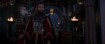 Movie still from “Aladdin” (2019), directed by Guy Ritchie – A man in a red and gold outfit standing in a room; Medium shot, Low angle