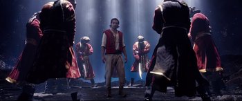 Movie still from “Aladdin” (2019), directed by Guy Ritchie – A group of men in costumes performing a dance; Wide shot, High angle