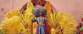 Movie still from “Aladdin” (2019), directed by Guy Ritchie – A man in a blue and gold costume with two women in yellow and purple costumes; Wide shot, Low angle