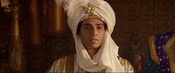 Movie still from “Aladdin” (2019), directed by Guy Ritchie – A young man wearing a white turban and a gold headpiece; Close Up shot, Low angle