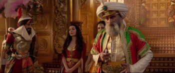 Movie still from “Aladdin” (2019), directed by Guy Ritchie – Two women and an old man standing in front of a wall; Medium shot, Over the shoulder angle