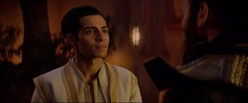Movie still from “Aladdin” (2019), directed by Guy Ritchie – A man wearing a white shirt and a white and gold jacket; Close Up shot, Over the shoulder angle