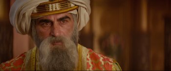 Movie still from “Aladdin” (2019), directed by Guy Ritchie – A man with a beard and a turban on; Close Up shot, Over the shoulder angle