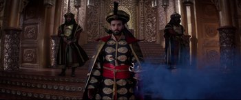 Movie still from “Aladdin” (2019), directed by Guy Ritchie – A man dressed in a black and gold costume; Wide shot, Low angle