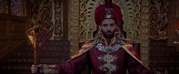 Movie still from “Aladdin” (2019), directed by Guy Ritchie – A man wearing a red turban and a red coat; Medium shot, Low angle