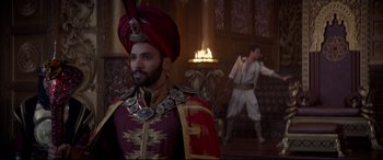 Movie still from “Aladdin” (2019), directed by Guy Ritchie – A man in a red turban and a man in a red and gold outfit; Medium shot, Over the shoulder angle