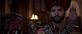 Movie still from “Aladdin” (2019), directed by Guy Ritchie – A man wearing a red turban and a red and gold outfit; Close Up shot, Over the shoulder angle
