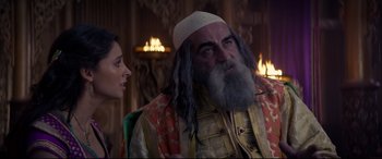 Movie still from “Aladdin” (2019), directed by Guy Ritchie – A man and a woman are sitting next to each other in front of candles; Medium shot, Over the shoulder angle