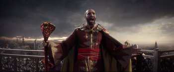 Movie still from “Aladdin” (2019), directed by Guy Ritchie – A man in a red and gold outfit is screaming; Medium shot, Low angle