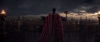 Movie still from “Aladdin” (2019), directed by Guy Ritchie – A man in a red and gold cape standing on a balcony; Wide shot, High angle