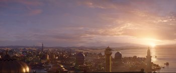 Movie still from “Aladdin” (2019), directed by Guy Ritchie – A view of a city skyline at sunset with a clock tower; Extreme Wide shot, High angle