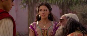 Movie still from “Aladdin” (2019), directed by Guy Ritchie – A woman with long hair wearing a purple and gold dress; Close Up shot, Over the shoulder angle