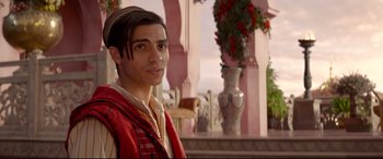 Movie still from “Aladdin” (2019), directed by Guy Ritchie – A man with long black hair wearing a red vest; Medium shot, Over the shoulder angle