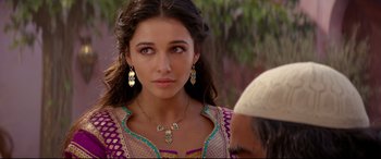 Movie still from “Aladdin” (2019), directed by Guy Ritchie – A beautiful young woman wearing a necklace and earrings while standing next to a man; Close Up shot, Over the shoulder angle