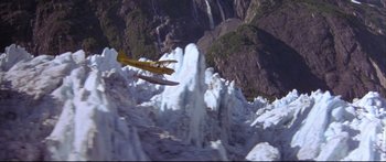 Movie still from “Alaska” (1996), directed by Fraser C. Heston – An airplane is flying over a waterfall and a mountain; Extreme Wide shot, High angle