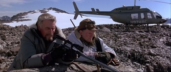 Movie still from “Alaska” (1996), directed by Fraser C. Heston – Two men sitting on the ground with a rifle; Medium shot, High angle