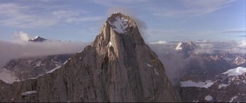 Movie still from “Alaska” (1996), directed by Fraser C. Heston – A helicopter flying over a mountain with snow on it; Extreme Wide shot, High angle