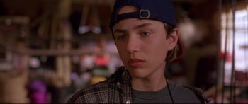 Movie still from “Alaska” (1996), directed by Fraser C. Heston – A young man wearing a blue hat and a plaid shirt; Close Up shot, Over the shoulder angle