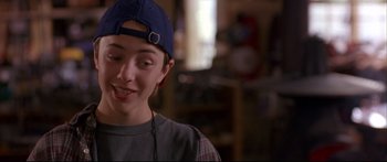 Movie still from “Alaska” (1996), directed by Fraser C. Heston – A young man wearing a baseball cap and a plaid shirt; Close Up shot, Over the shoulder angle
