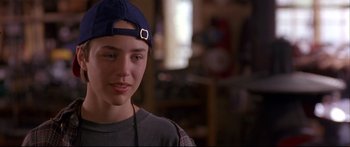 Movie still from “Alaska” (1996), directed by Fraser C. Heston – A young man wearing a baseball cap and a plaid shirt; Close Up shot, Over the shoulder angle