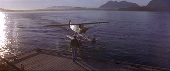 Movie still from “Alaska” (1996), directed by Fraser C. Heston – A man standing next to a water plane on the water; Wide shot, High angle
