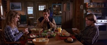 Movie still from “Alaska” (1996), directed by Fraser C. Heston – A man sitting at a table with a plate of food; Medium shot, High angle
