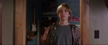 Movie still from “Alaska” (1996), directed by Fraser C. Heston – A young man standing in front of a wall with guitars; Close Up shot, Low angle