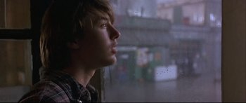 Movie still from “Alaska” (1996), directed by Fraser C. Heston – A young man looking out a rainy window; Close Up shot, Low angle