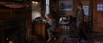 Movie still from “Alaska” (1996), directed by Fraser C. Heston – A woman sitting at a desk in front of a computer; Wide shot, High angle
