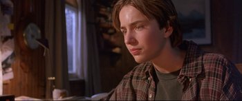 Movie still from “Alaska” (1996), directed by Fraser C. Heston – A young man sitting in front of a window; Close Up shot, Low angle