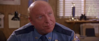 Movie still from “Alaska” (1996), directed by Fraser C. Heston – A man that is wearing a police uniform; Close Up shot, Over the shoulder angle
