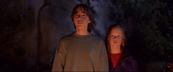 Movie still from “Alaska” (1996), directed by Fraser C. Heston – A boy and a girl standing next to each other in front of a cave; Medium shot, Low angle
